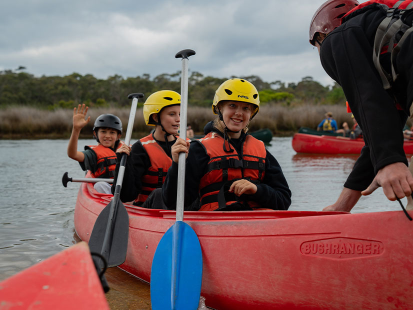 Young people sitting in canoe