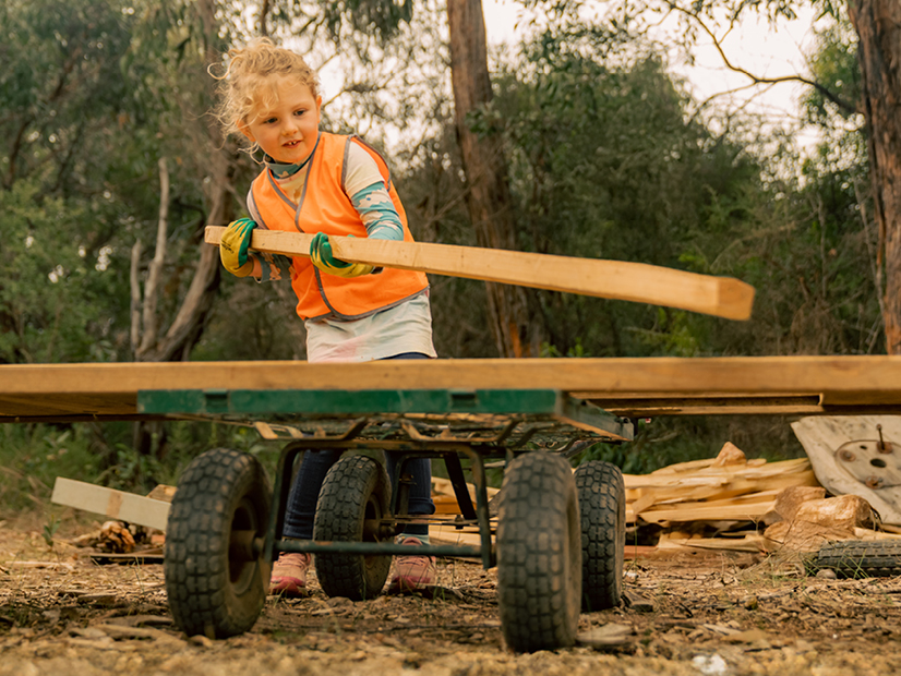 Young girl helping load a cart with wood for a camp fire